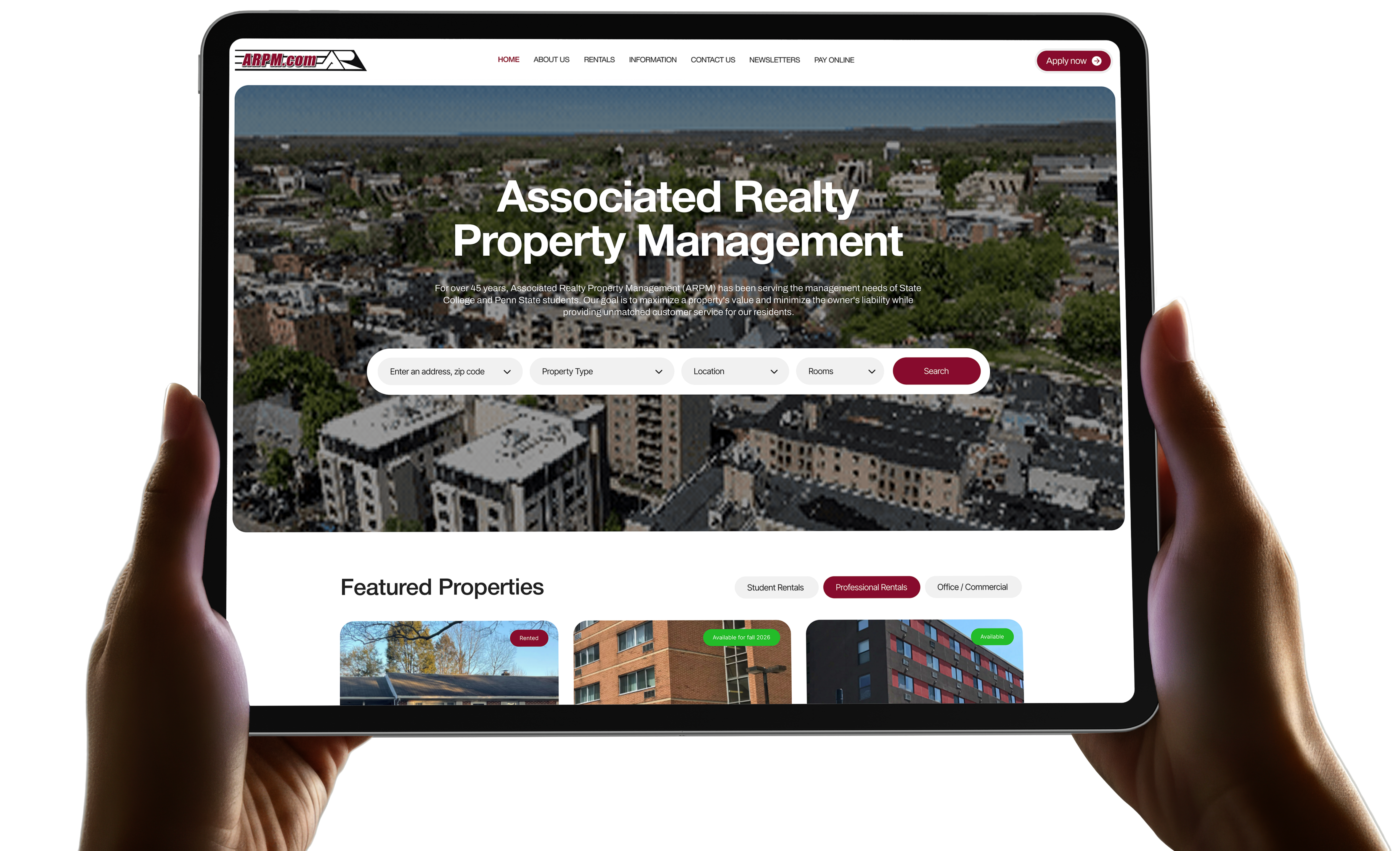 Hands holding an iPad displaying the redesigned Associated Realty Property Management website